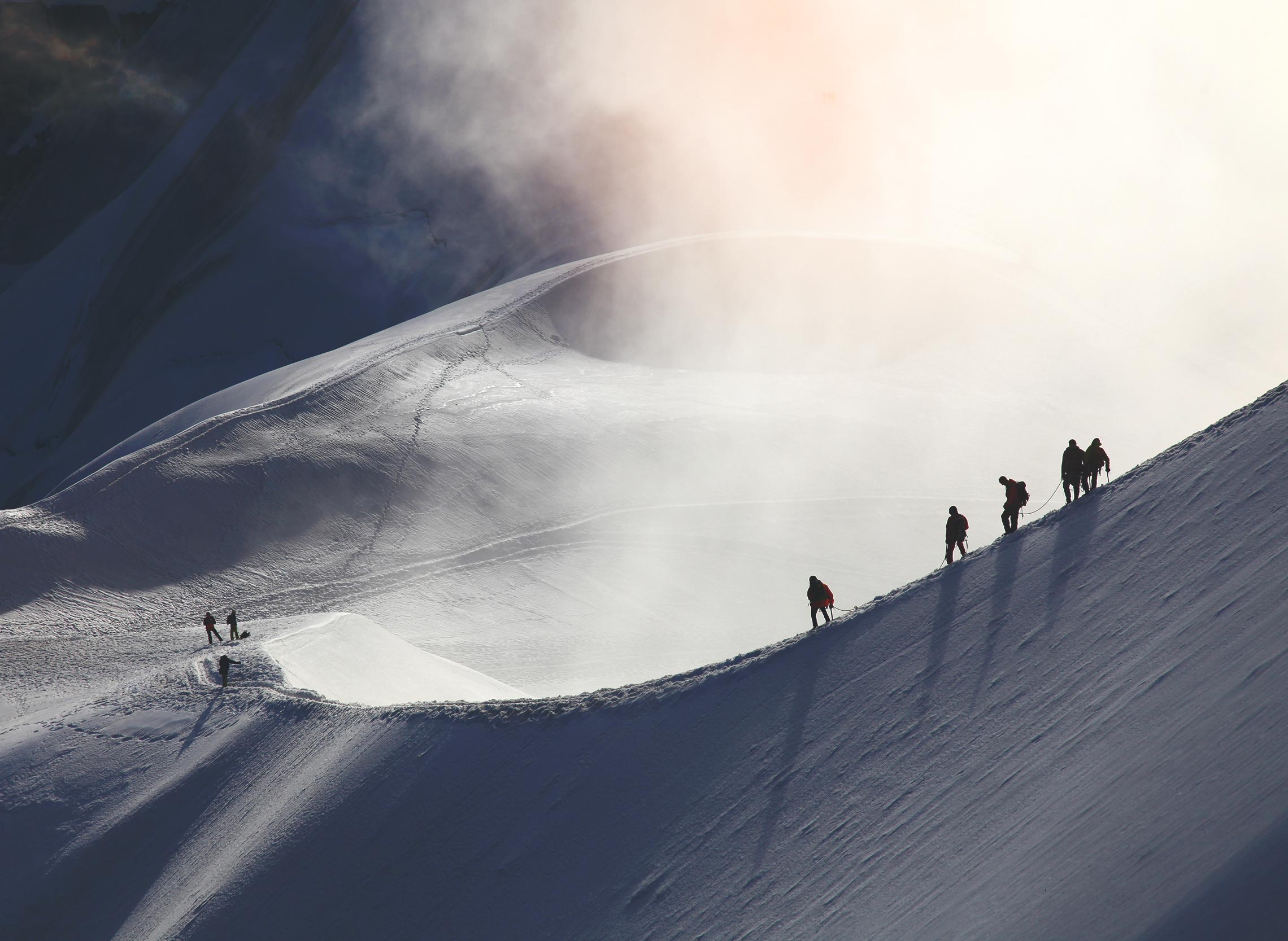 Climbers ascending a snow-covered Norwegian mountain ridge